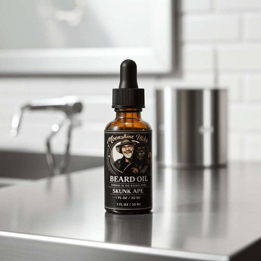 Fort Denaud Beard and Skin Moonshine Mike Skunk Ape beard oil in an amber glass dropper bottle on a metal counter.