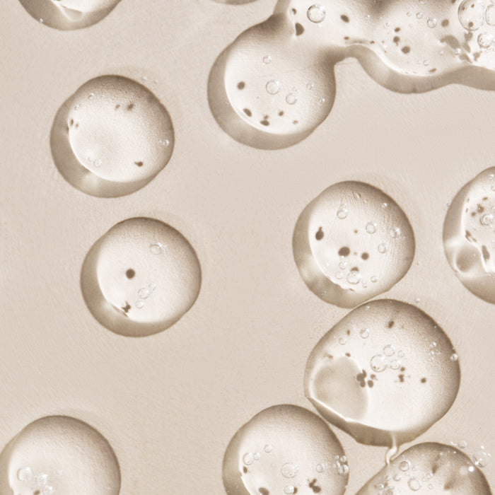 Close-up of hydrating serum droplets with micro-bubbles on skin, showcasing lightweight texture for all skin types