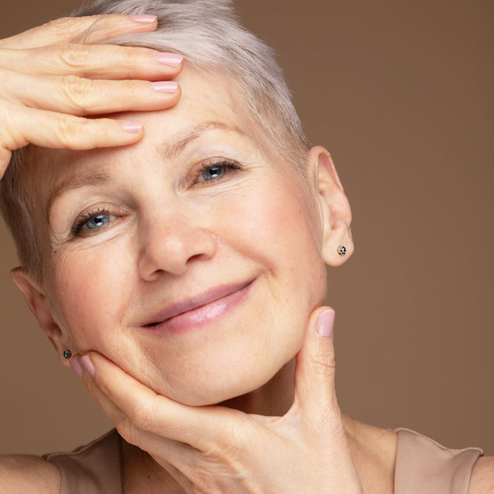 Mature woman with radiant skin gently touching her face, showcasing natural beauty and anti-aging skincare results.