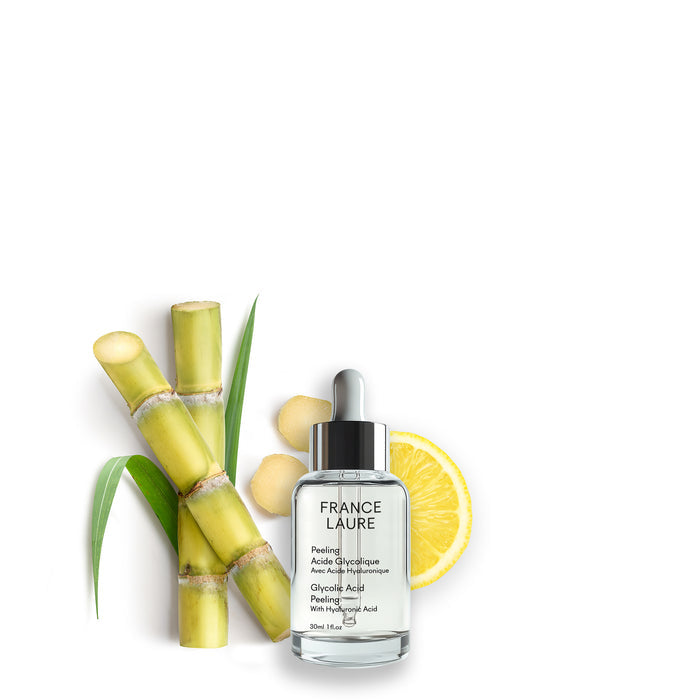 France Laure Glycolic Acid Peeling with Hyaluronic Acid in clear dropper bottle, surrounded by sugarcane, lemon slice, and ginger for natural skincare
