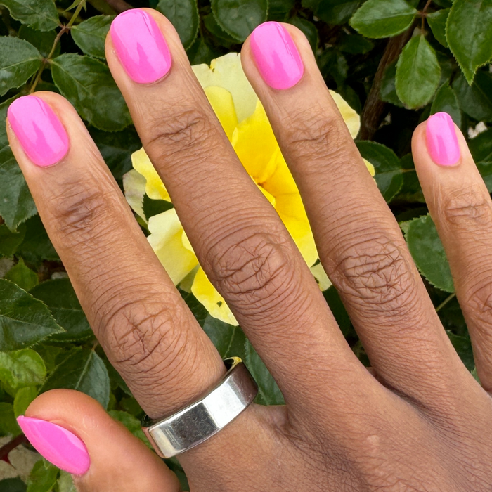 Peony | Extra Short | Round - Tab Press-On nails in bright pink glossy finish shown on hand with silver ring outdoors