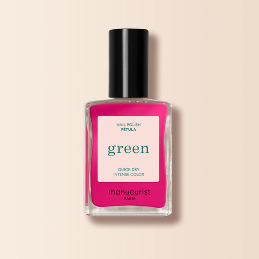 A bottle of Manucurist Pétula nail polish features vibrant pink with blue undertones from the Green range, a black cap, and a cream label with green and pink text on light beige.