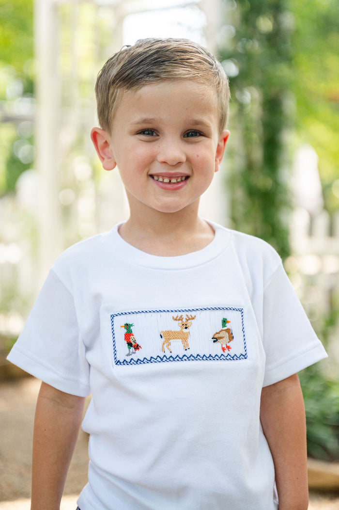 Close-up of boy smiling in Smocked Hunting T-Shirt by Ruth and Ralph, showing smocked deer embroidery detail