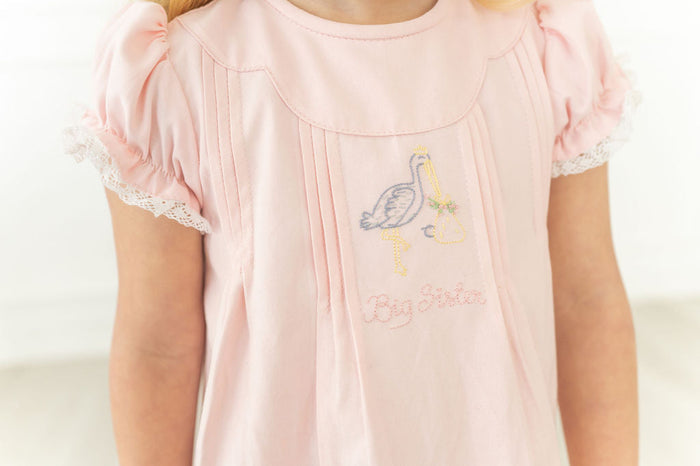 A little girl will feel so proud wearing this charming dress, featuring delicate stork embroidery and "Big Sister" lettering.