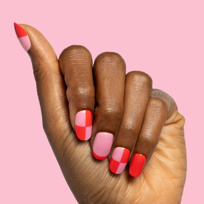 Pink Checker Party | Short | Round - Tab Press-On showing hand with pink and red checker false nails on soft pink background