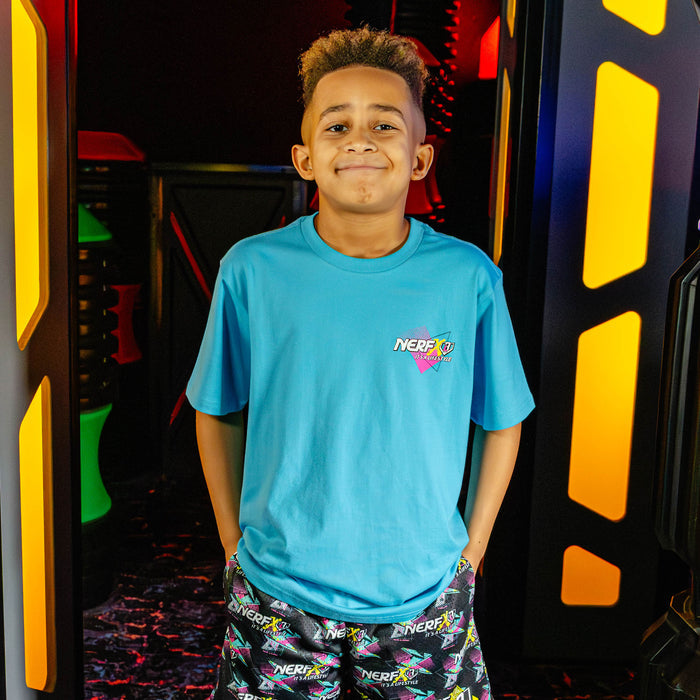 Child wearing a blue t-shirt with a 'NERF  X BL101' logo in an indoor play area