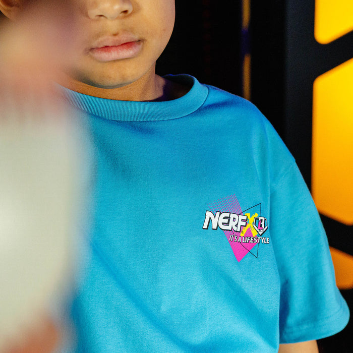 Child wearing a blue t-shirt with a 'NERF  X BL101' logo in an indoor play area