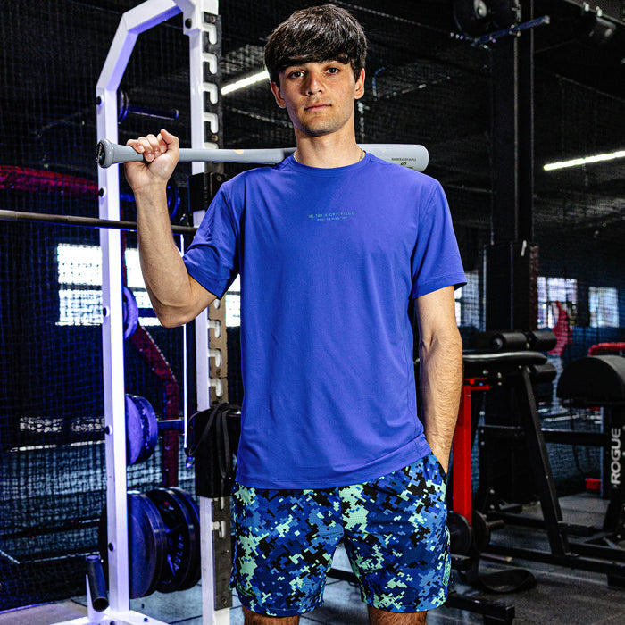 Person wearing a blue t-shirt and patterned shorts in a gym setting