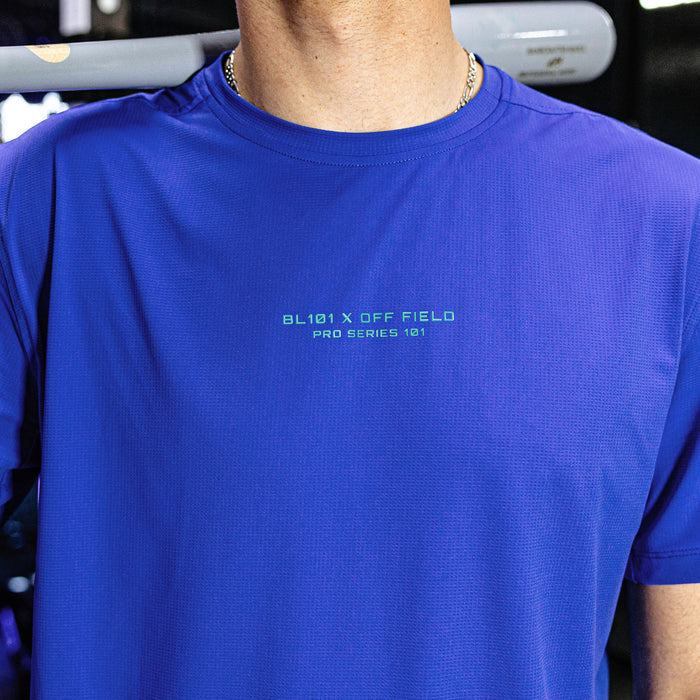Person wearing a blue athletic shirt with text on it, standing in front of a blurred background.