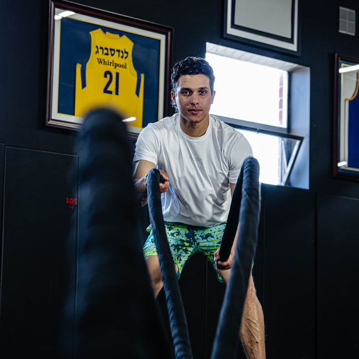 Man exercising with resistance bands in a room.