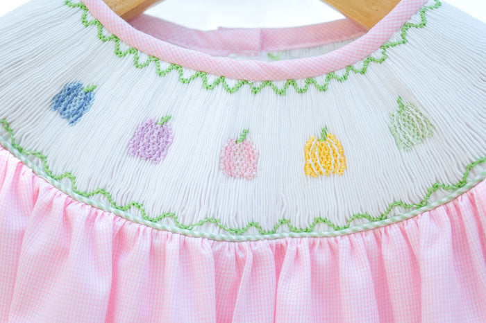 Close-up of smocked rainbow pumpkins embroidery detail on Ruth and Ralph pink dress