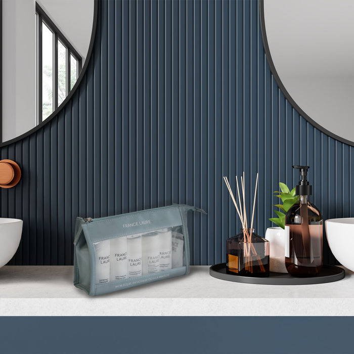 France Laure travel skincare set in mint pouch with cleansing milk, toner, and cream, displayed on bathroom counter beside diffuser and soap dispenser
