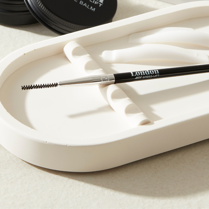 Eyebrow micro brush with 'London' branding on a white tray