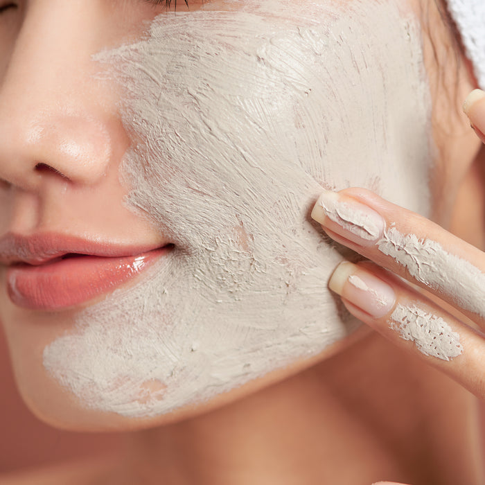 Woman applying creamy clay face mask for deep pore cleansing and skin detox, gentle skincare routine for all skin types