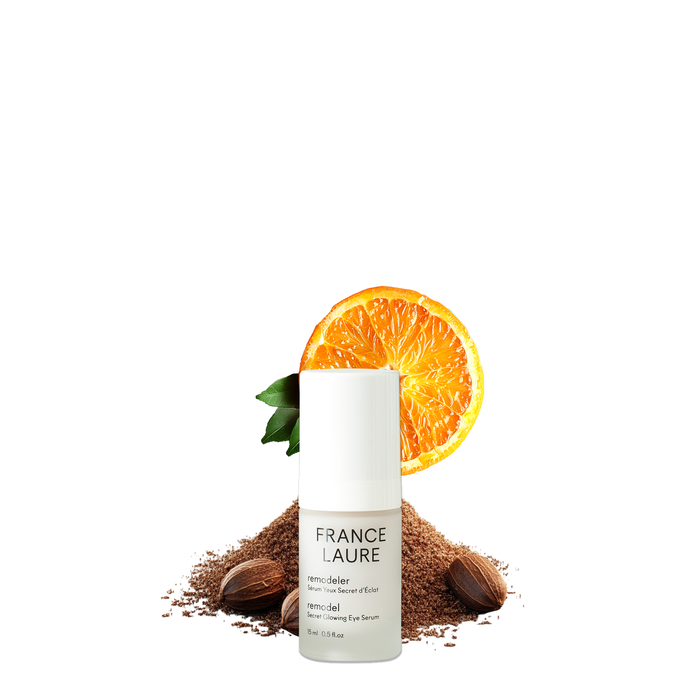 France Laure Remodel Secret Glowing Eye Serum bottle with orange slice, nuts, and brown powder, showcasing natural skincare ingredients for radiant eye care.