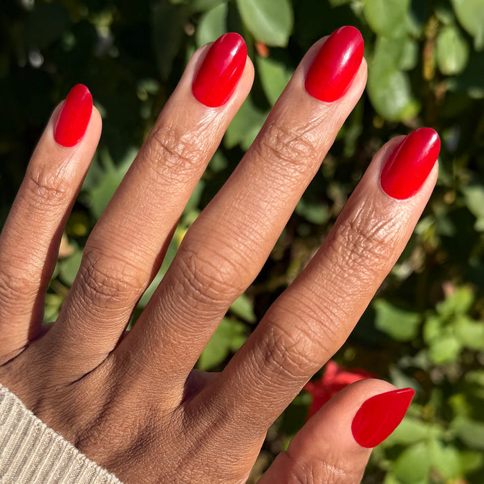 Hand with medium oval press-on nails in bright blue-toned red shade Secret Recipe - Press-On | Medium | Oval outdoors