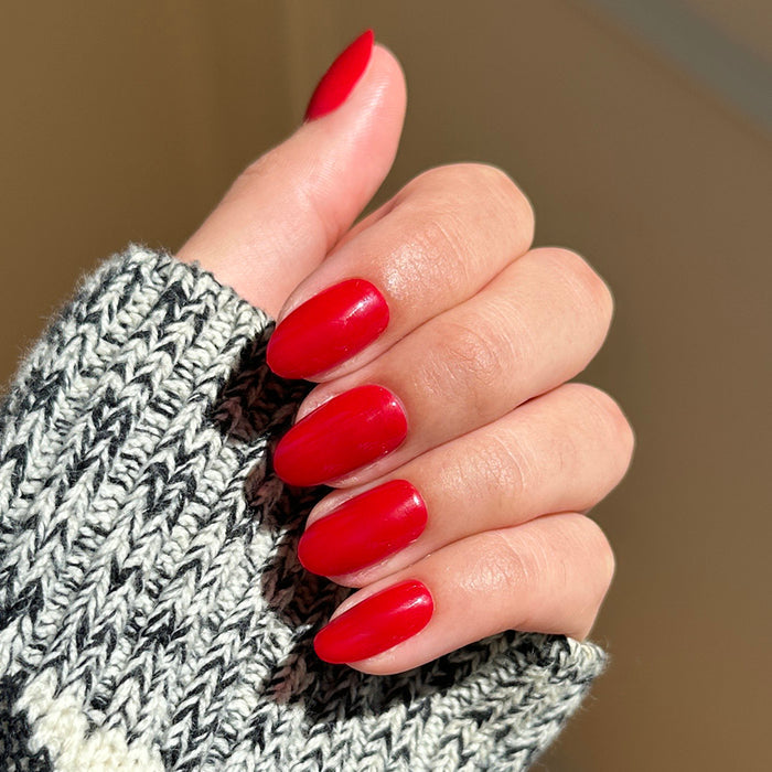 Hand with medium oval nails in blue-toned red shade Secret Recipe - Press-On | Medium | Oval worn with knit sweater