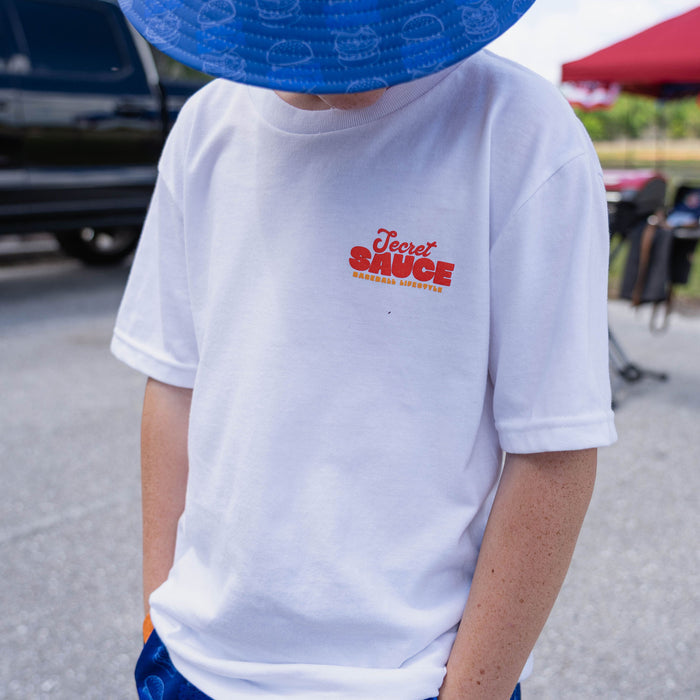 Person wearing a white t-shirt with 'Secret Sauce' logo outdoors