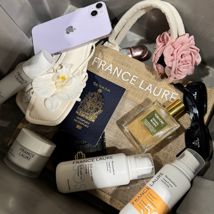 France Laure skincare essentials with SOS after-sun, Intense 50 protection, and Tom Ford Soleil Blanc oil, styled with travel accessories and a passport.