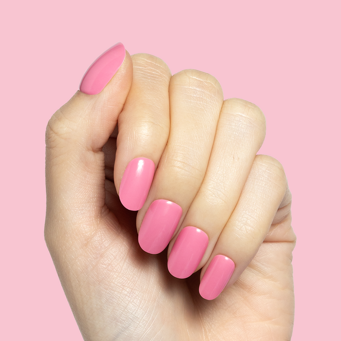 Taffy | Short | Round - Tab Press-On showing bright pink glossy false nails on hand with a pink background