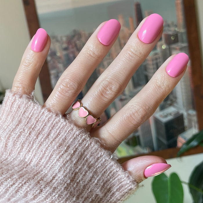 Taffy | Short | Round - Tab Press-On showing bright pink glossy press-on nails on hand with cozy sweater background