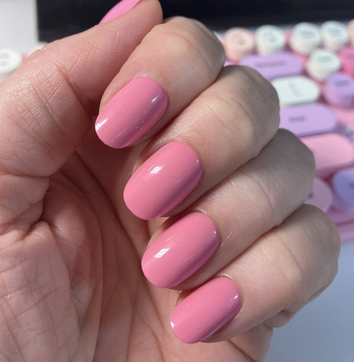 Taffy | Short | Round - Tab Press-On showing smooth glossy sugary pink press-on nails on hand with colorful keyboard background