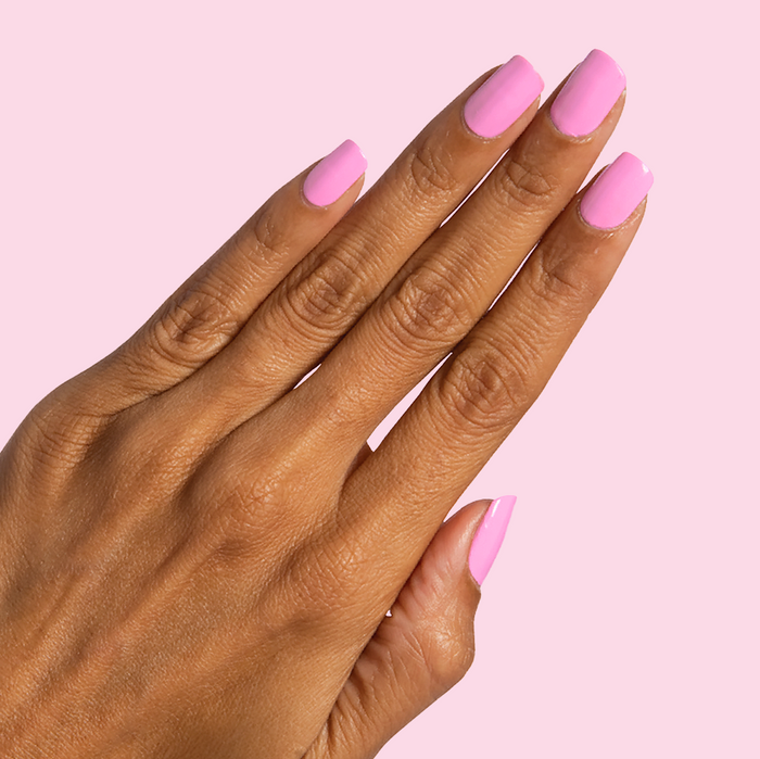 Hand with Taffy bright pink quick dry gel polish on neatly manicured nails against pale pink background