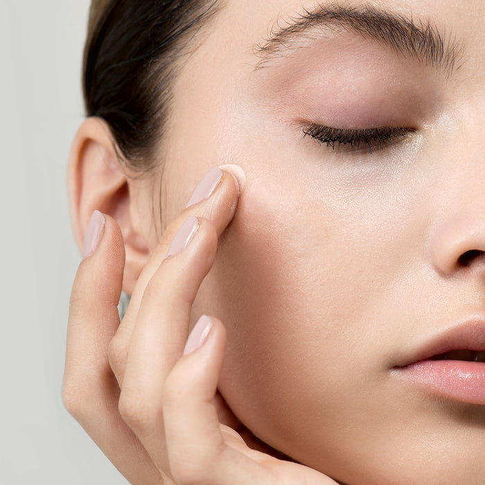 Woman applying gentle skincare cream to cheek with soft touch, showcasing smooth, radiant skin texture for all ages