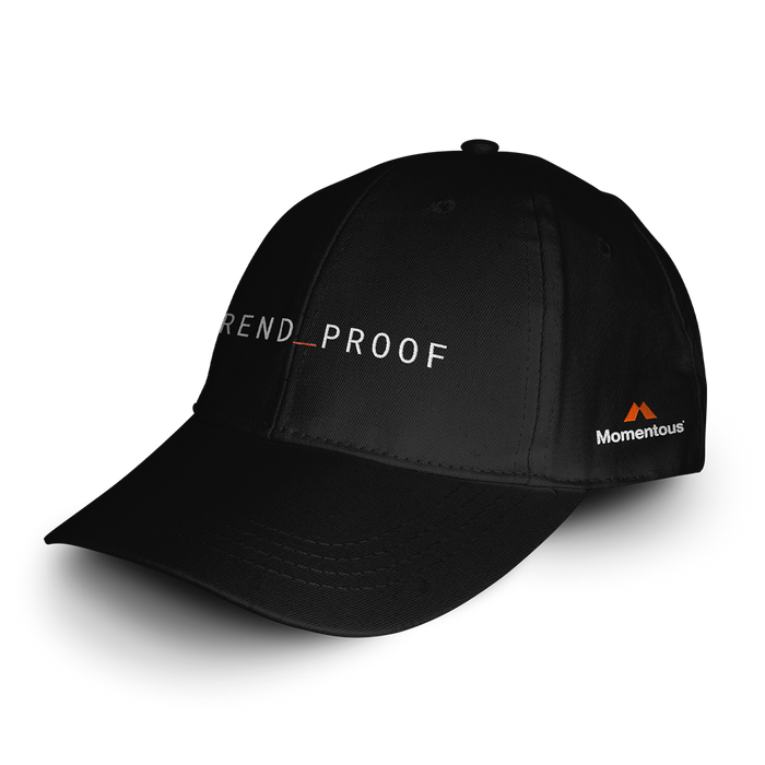 Black “TREND_PROOF” baseball cap angled to show front logo in white with red underscore and the Momentous logo embroidered in white and orange on the side.