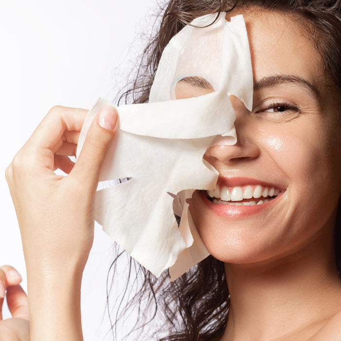 Woman removing hydrating sheet mask, revealing glowing skin — ideal for all skin types and ages, gentle skincare routine
