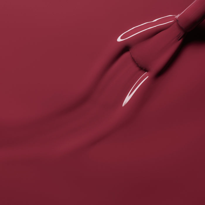 A close-up of a brush applying Manucurist's Victoria Plum nail polish, creating smooth and shiny strokes across the surface.