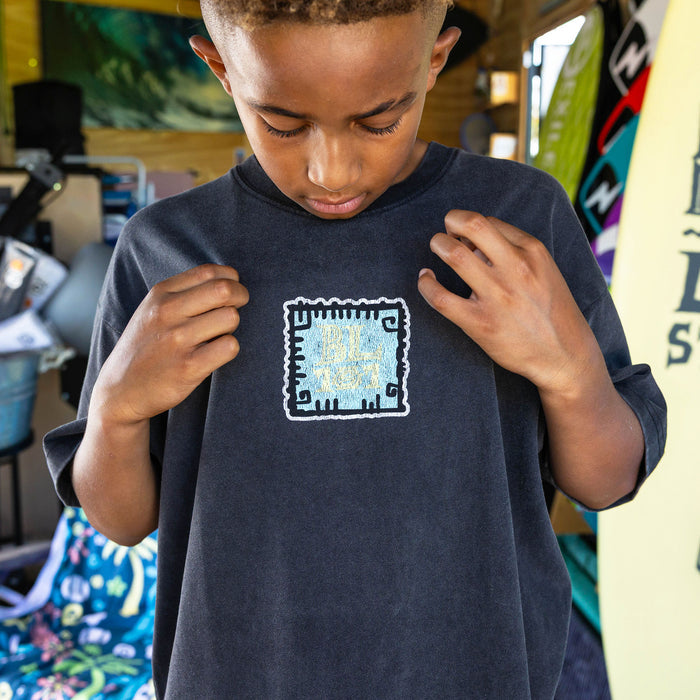 Youth model wearing black youth graphic tee with "Wave Goodbye" design