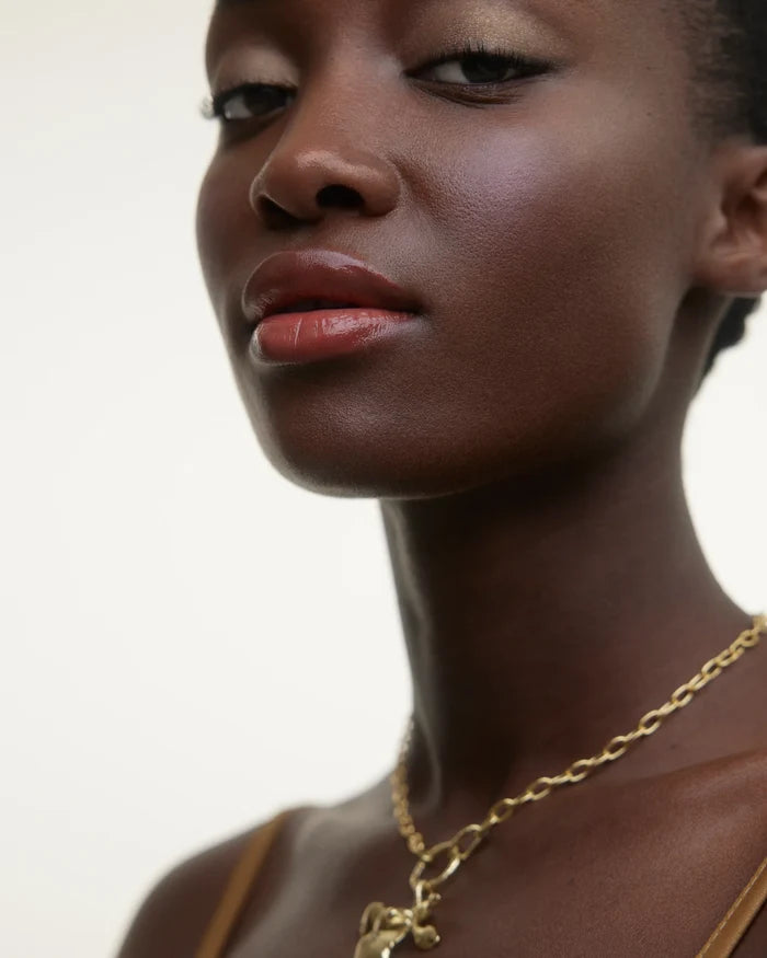 WONDERBLUSH La Laque Tinted Lip Oil in Abricot, applied on dark skin, showcasing a glossy, natural lip finish.